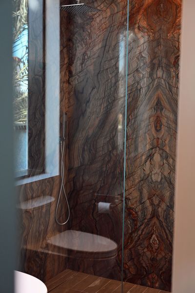 Small bathroom with marble-look tiled shower, window, and wall-mounted toilet paper holder