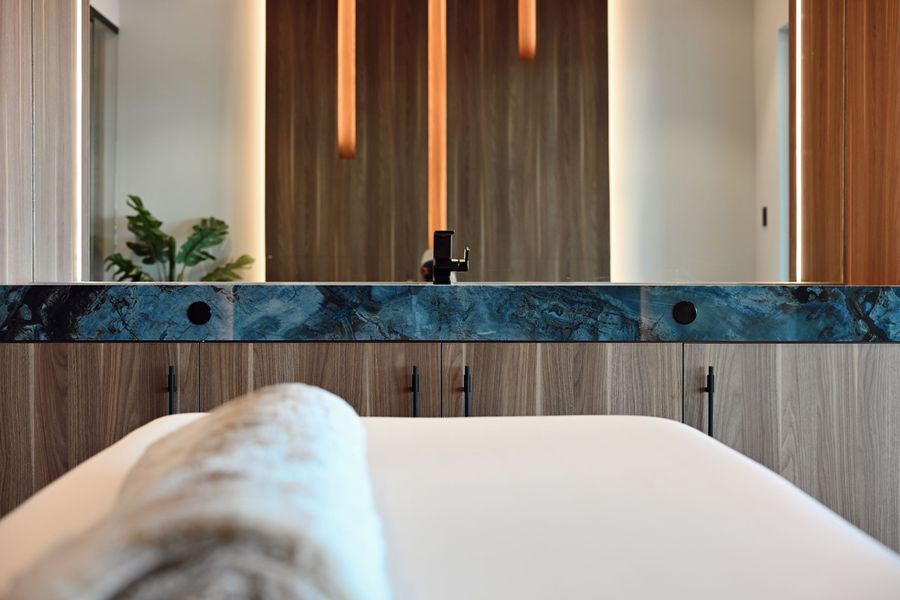 Modern bathroom with white tub, wood paneling, marble vanity, and soft warm lighting