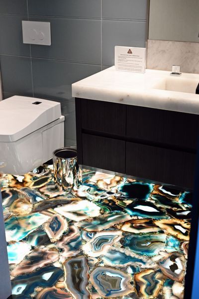 Bathroom vanity with sink, toilet, and patterned countertop in teal, black, and white.