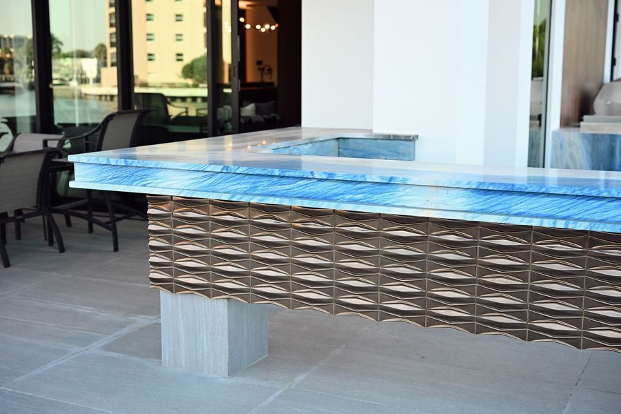 Outdoor table with blue glass top and woven metal base on a patio