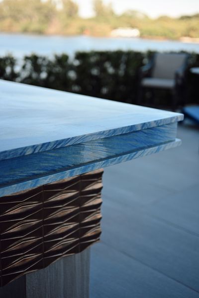 Blue glass tabletop with woven base on an outdoor patio