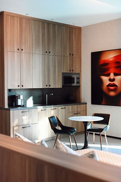Modern kitchen nook with wood cabinets, round table, and chair; bold red portrait hangs on the wall.