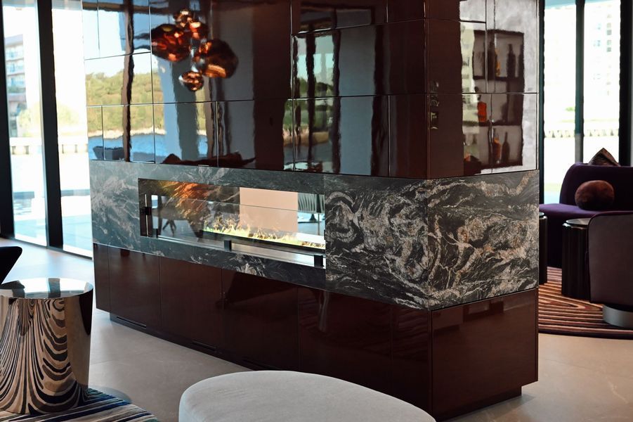 Modern living room with a marble fireplace, glass partition, and pendant light in a contemporary interior