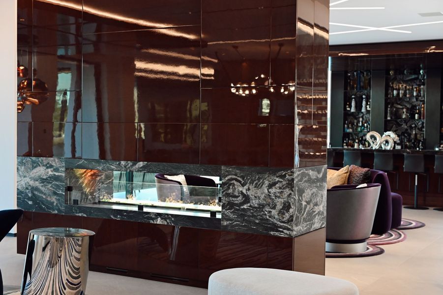 Modern lounge with glossy dark walls, mirrored surfaces, and marble accents near plush seating