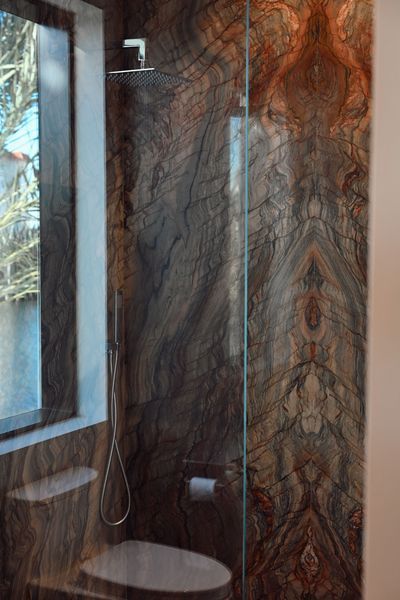 Modern bathroom shower with patterned stone wall and window letting in natural light