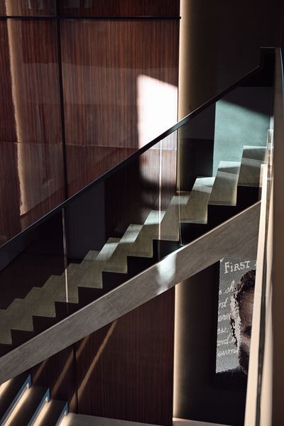 Modern staircase with glass railing and dark wood walls in a dim interior