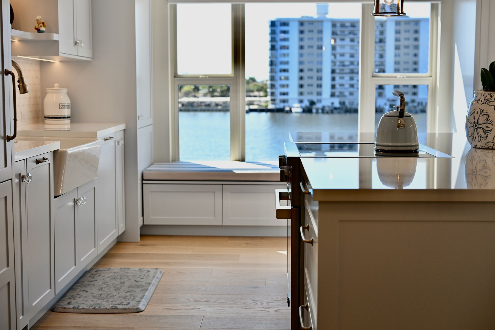 Bright kitchen with island, white cabinets, and large window overlooking water and city buildings