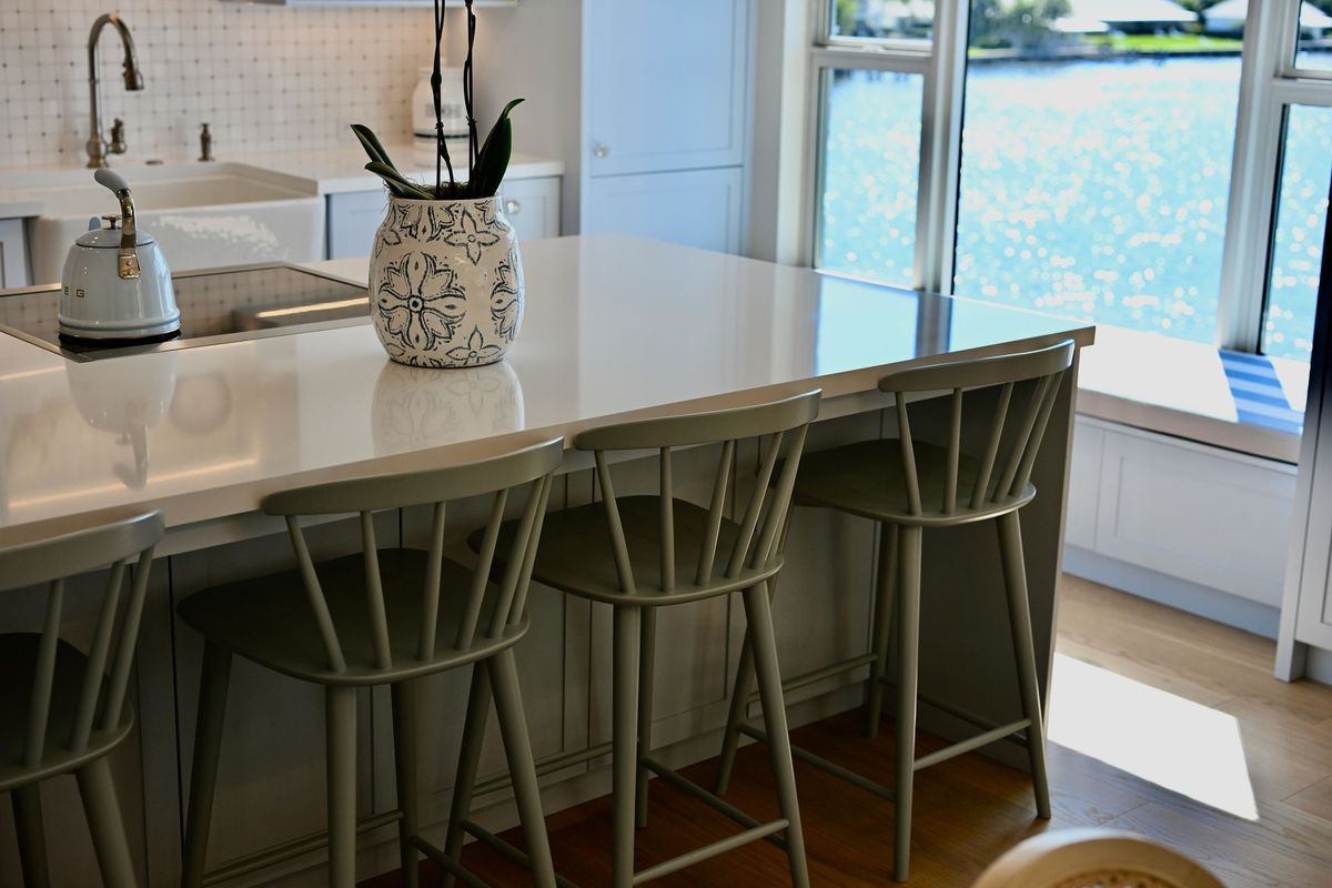 Modern kitchen island with four green barstools, countertop decor, and bright window light