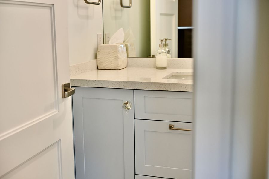 Small white bathroom vanity with sink, mirror, and door partially open.