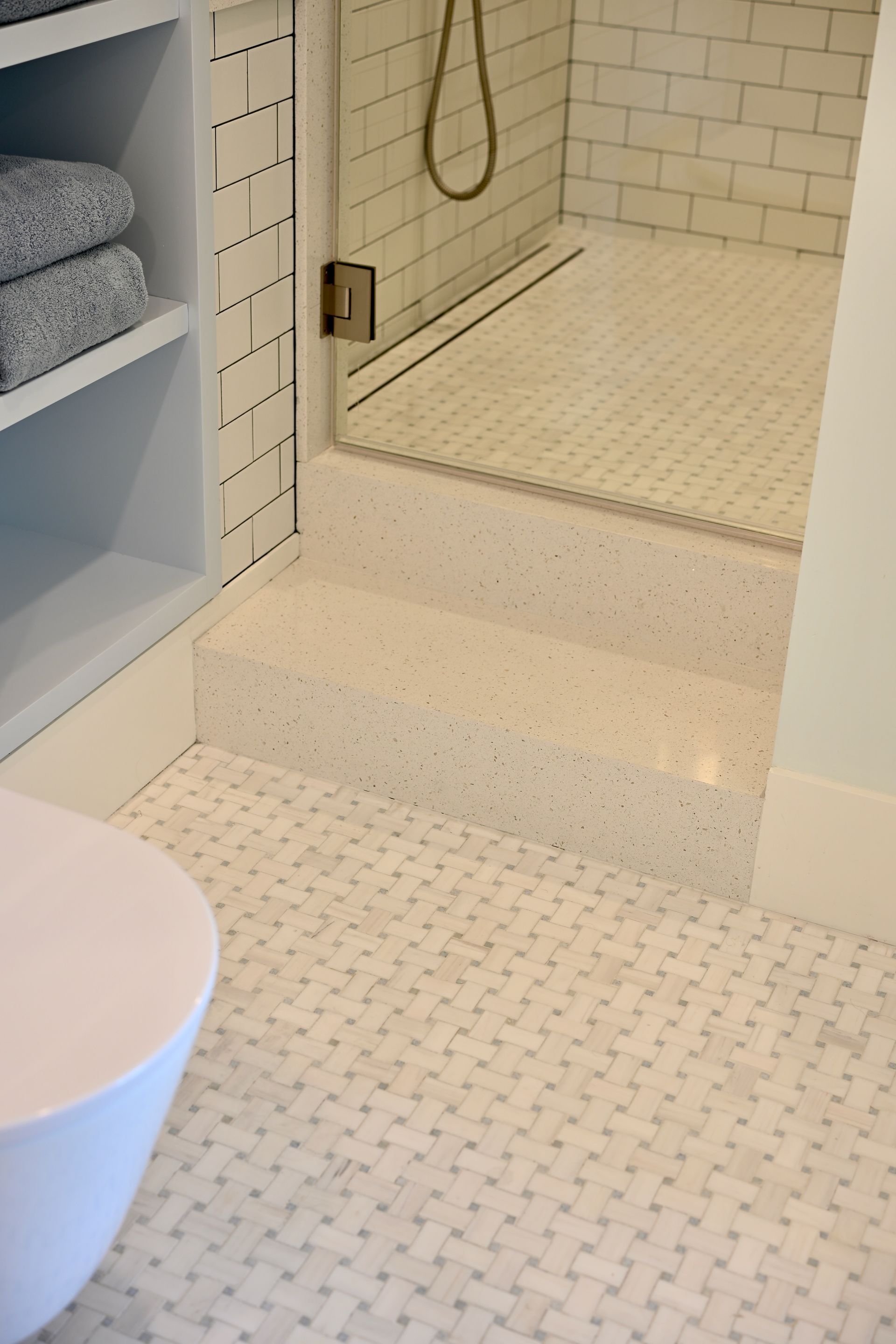 Small mosaic-tiled bathroom with a step-up shower and white fixtures