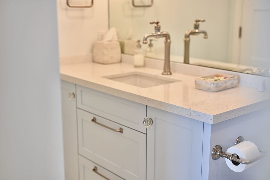 White bathroom vanity with sink, mirror, soap dispenser, and toilet paper holder