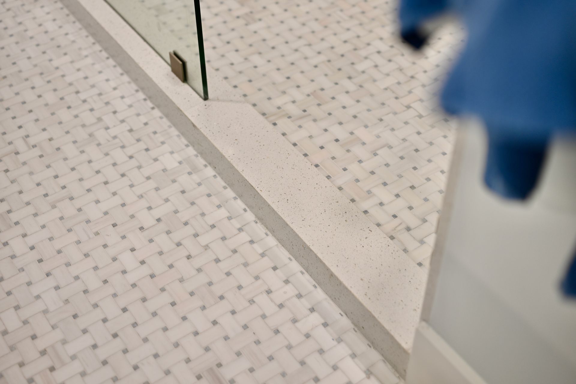 Bathroom floor with small square tiles, a mirror, and a blue towel at the edge