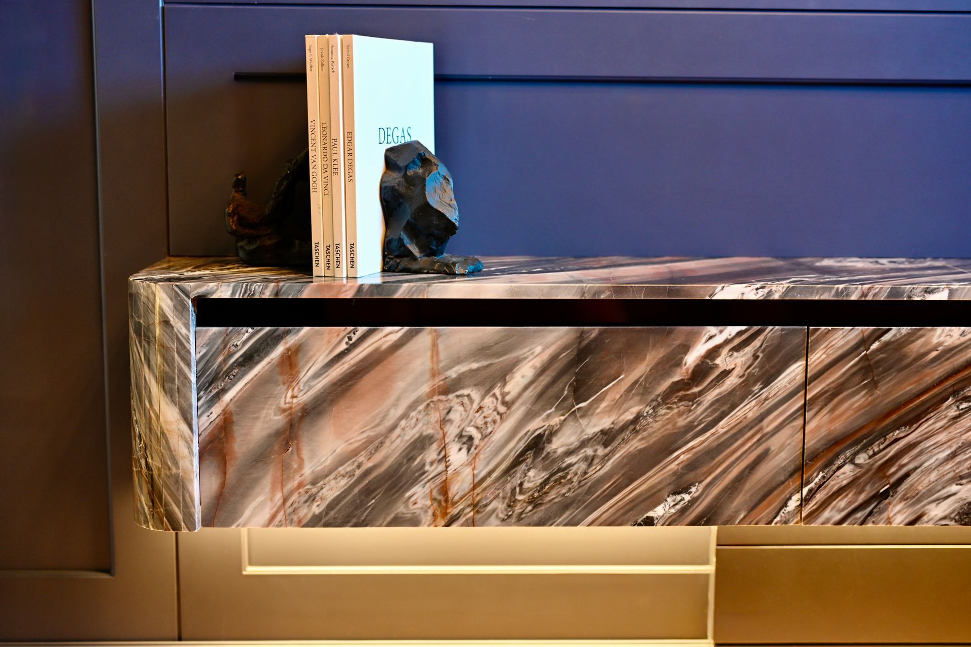 Marbled countertop with a decorative book and small figurine against a dark wall and warm underlighting