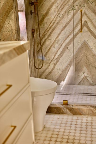 Modern bathroom with a shower, toilet, and marble-patterned walls and floor.