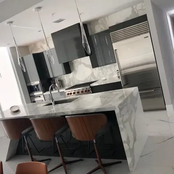 Modern kitchen with marble island, three stools, stainless steel appliances, and dark cabinets