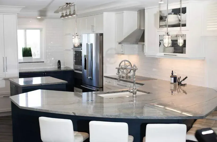 Modern white kitchen with black countertops, stainless steel appliances, and a large curved island with bar stools