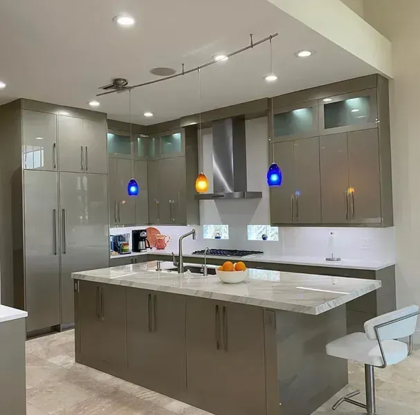 Modern kitchen with gray cabinets, island, pendant lights, and stainless steel appliances