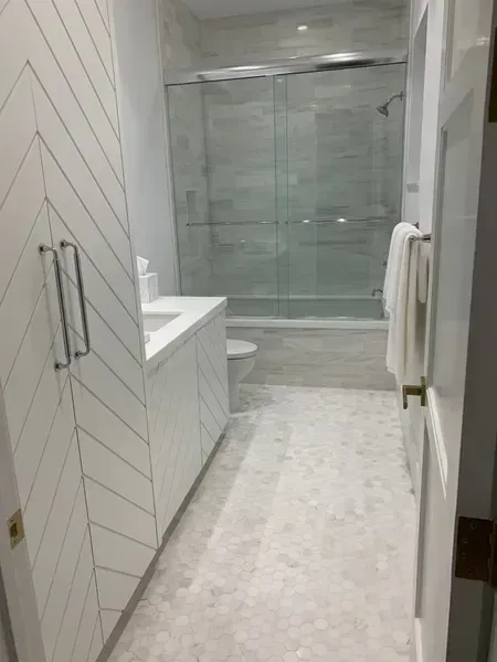 Modern bathroom with glass shower, white vanity, and tiled floor
