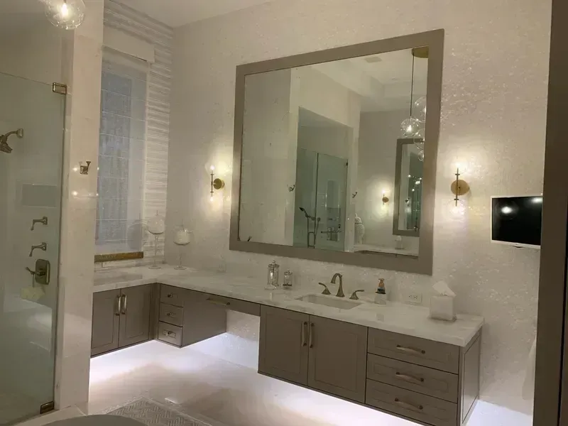 Modern bathroom with large mirror, double vanity, glass shower, and soft wall lighting
