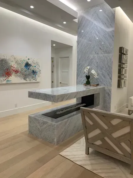 Modern minimalist living room with marble fireplace, abstract wall art, and light wood flooring