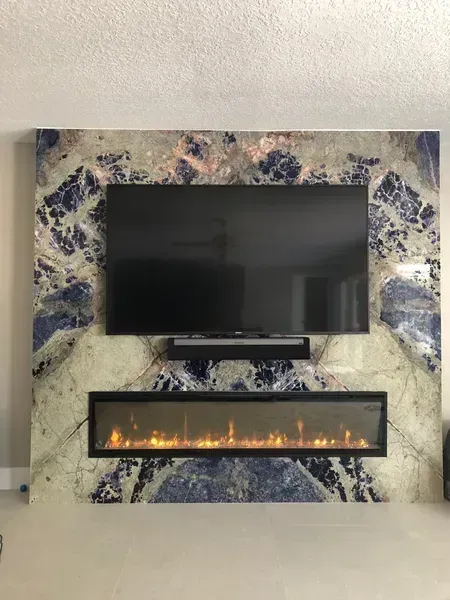 Modern wall-mounted TV above a horizontal fireplace on a blue-and-white marbled accent wall