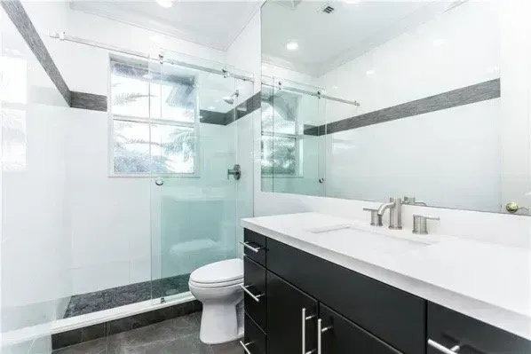 Modern bathroom vanity with white sink, large mirror, gray cabinet, and shelves with decor