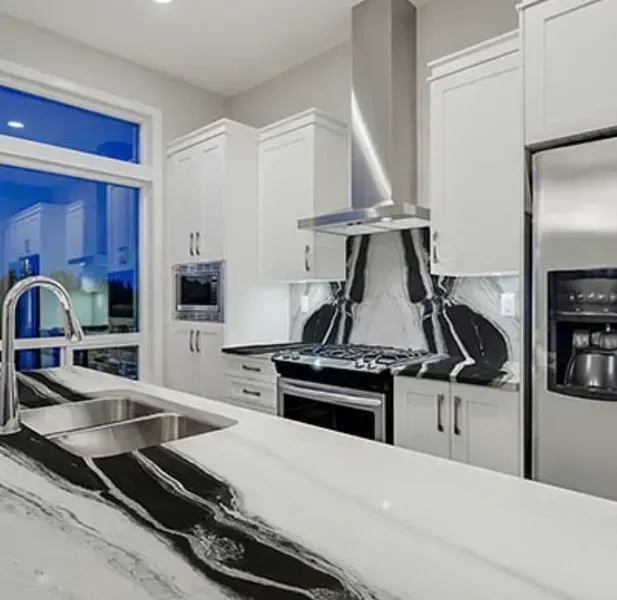 Modern white kitchen with black marble countertops, stainless steel appliances, and a large window