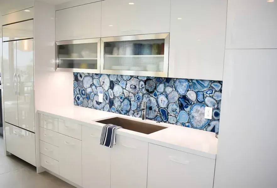 Modern white kitchen with glossy cabinets and blue floral tile backsplash