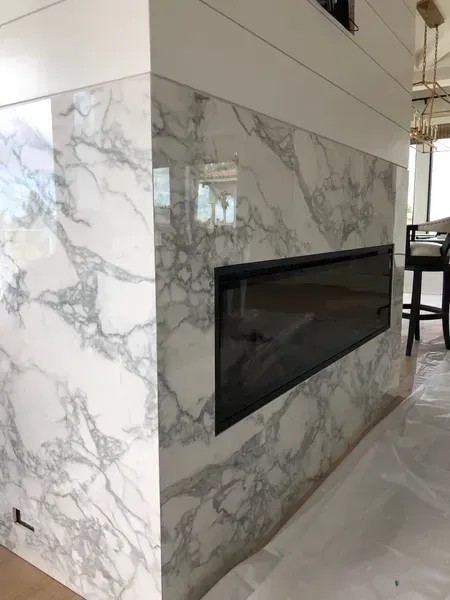 Marble-clad modern fireplace with a black glass insert in a bright interior