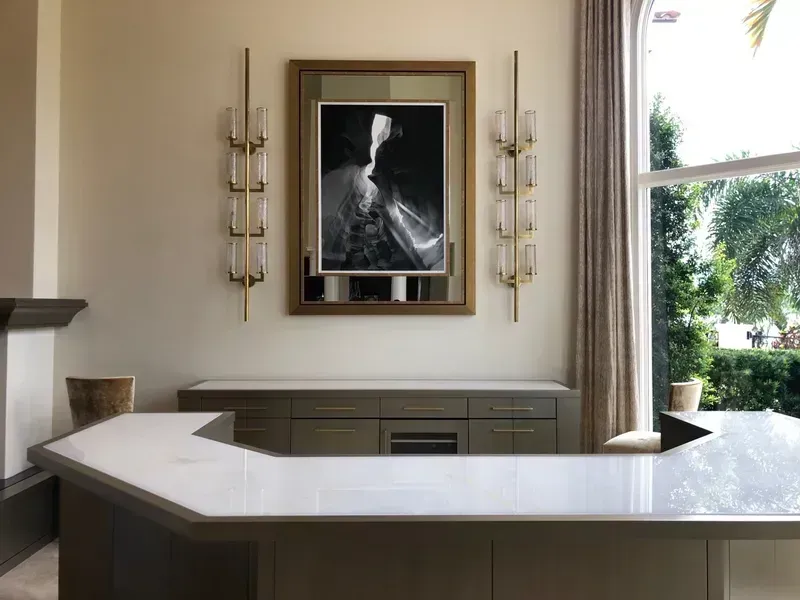 Modern fireplace alcove with framed black-and-white art, wall sconces, and a glossy white counter in front