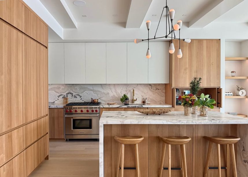 Modern kitchen with wood island, marble counters, white cabinets, and pendant lights