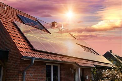 Two men are installing solar panels on the roof of a house.