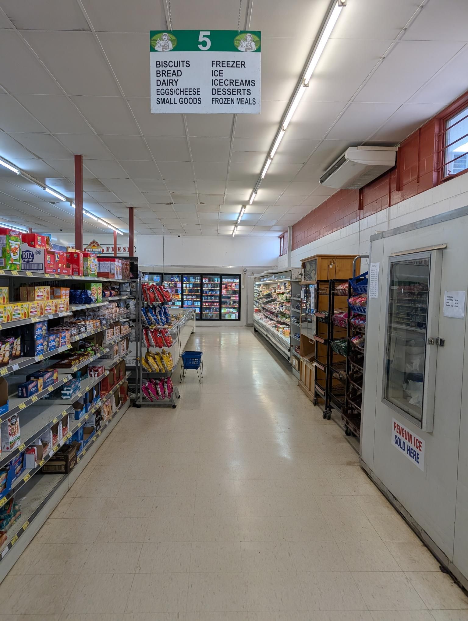 A Woman is Holding a Package of Meat in Front of a Shelf of Meat — Howard Springs Supermarket In Howard Springs, NT