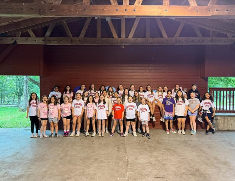 Large group standing in a wooden pavilion, posing for a group photo with a forested background.