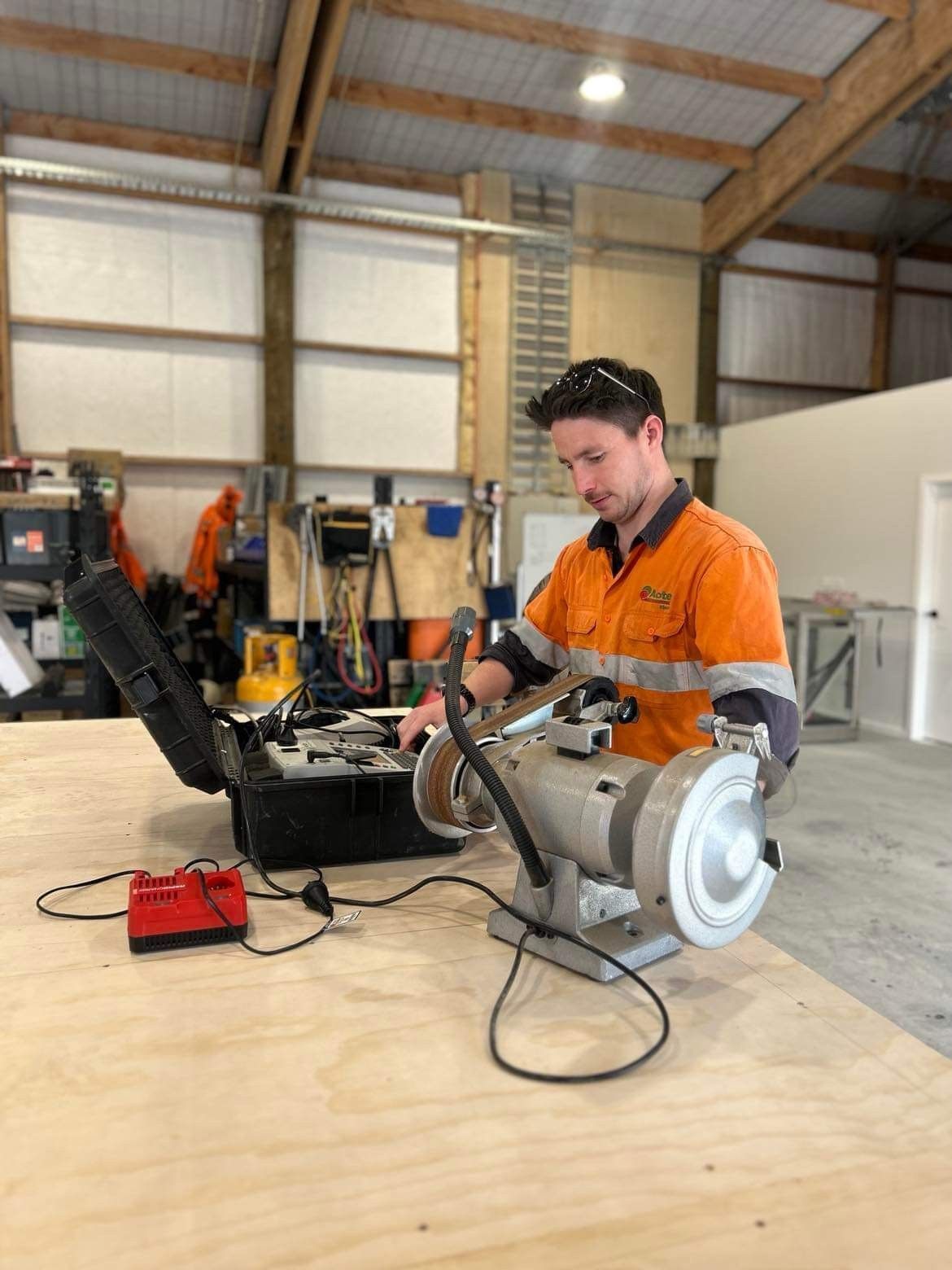 Electrician tests an outlet with a multimeter, wearing gloves and working on a ceiling.