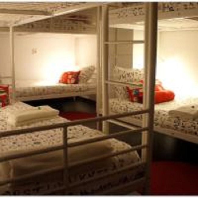 White bunk beds in a small dorm room with patterned bedding and red accents