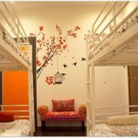 Cozy dorm room with white bunk beds, an orange accent wall, and a floral wall decal above a pink chair