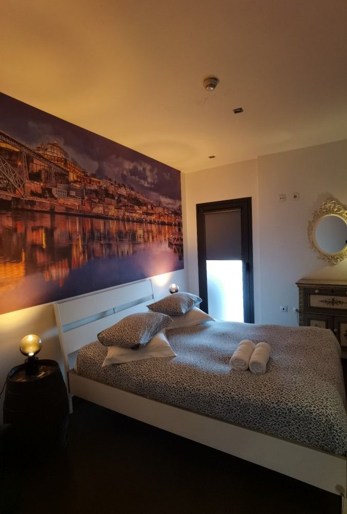 Cozy bedroom with large cityscape wall art, neatly made bed, and warm ambient lighting