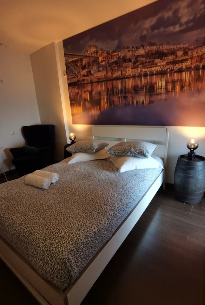 Modern bedroom with a made bed, cityscape wall art, and warm bedside lighting