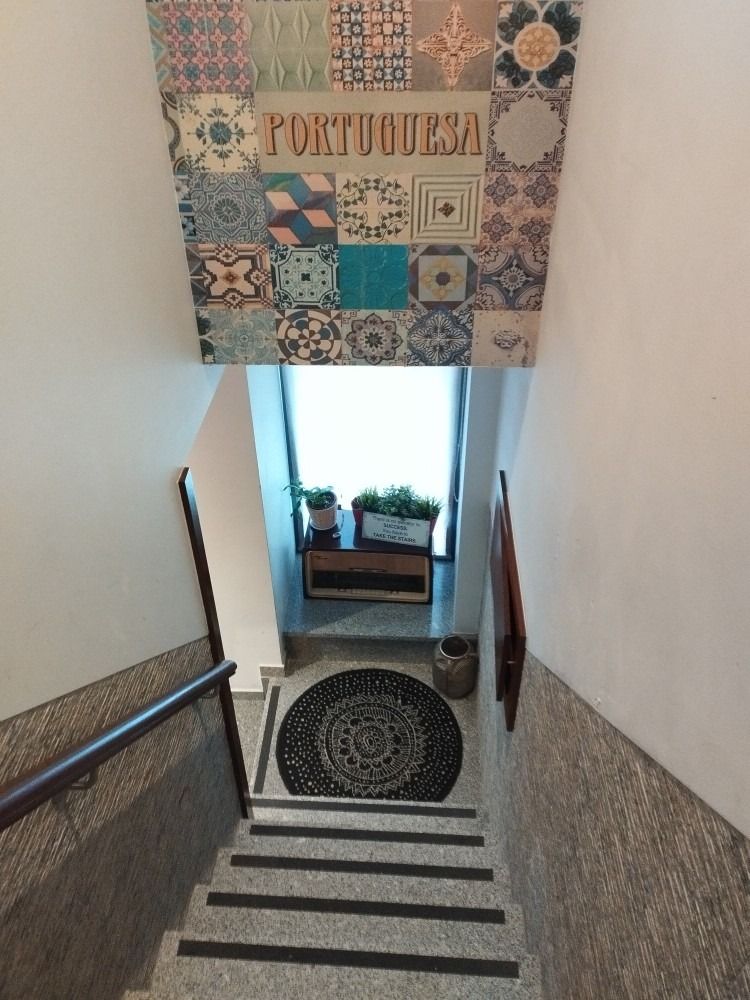 Stairwell with patterned wall art, striped steps, and a bright landing with potted plants.
