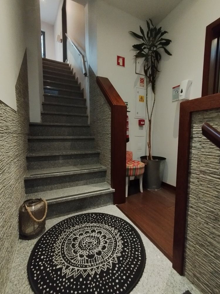 Indoor stairwell with patterned black rug, potted plant, and wood-paneled walls