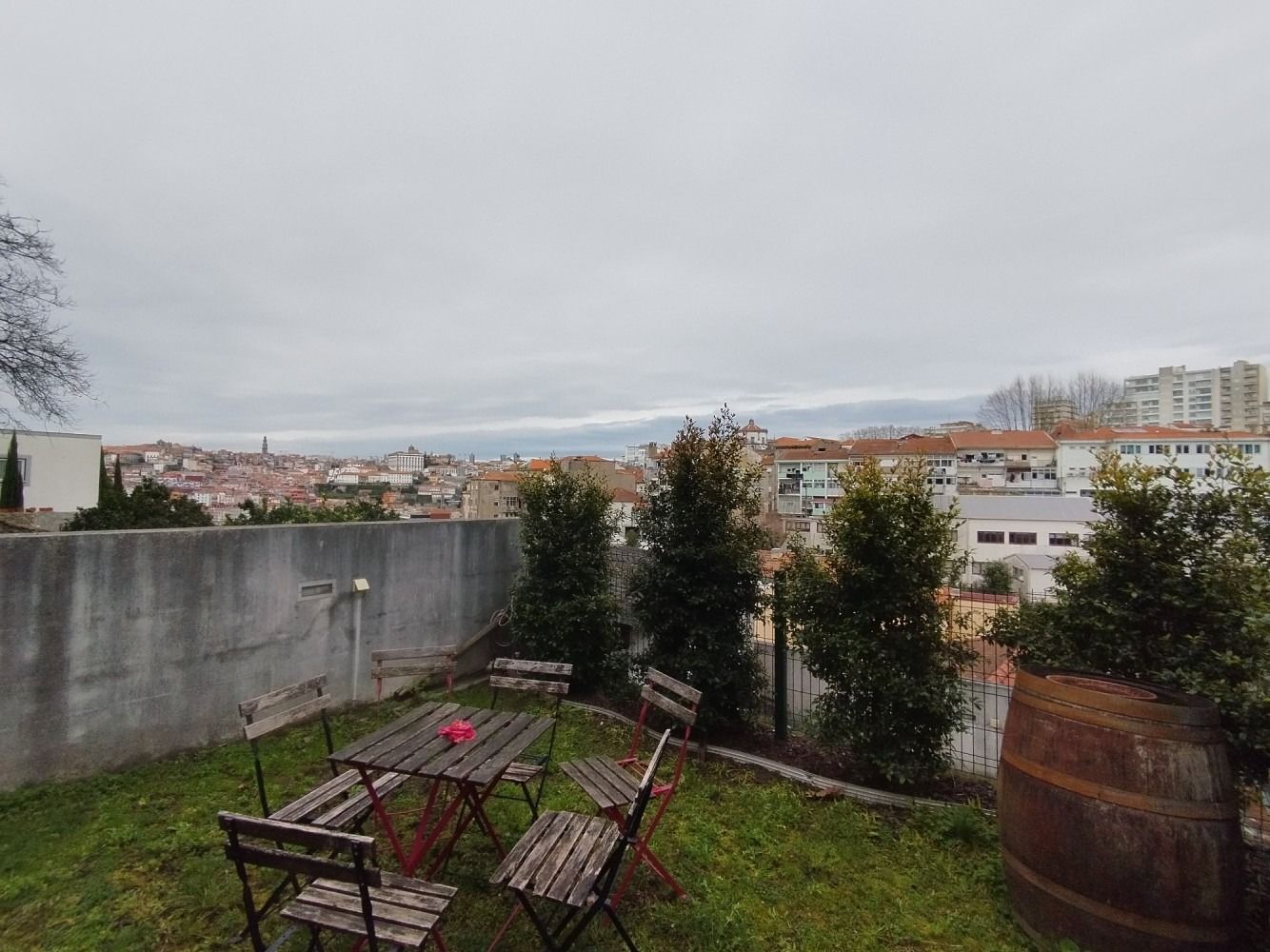Patio with picnic tables and benches overlooking a city skyline under a cloudy sky