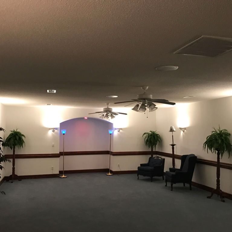 A mostly empty room with blue carpet, white walls, and two blue armchairs.