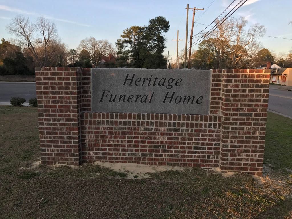 Brick sign for Heritage Funeral Home with gray stone text.