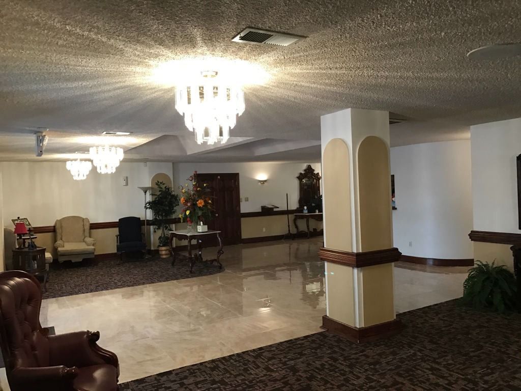 Interior of a building with chandeliers, seating areas, and a shiny tiled floor.