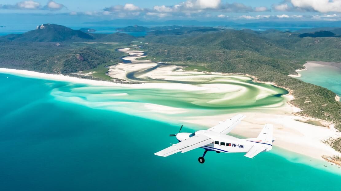 Aerial view of Whitehaven Beach in the Whitsundays with a small plane flying over