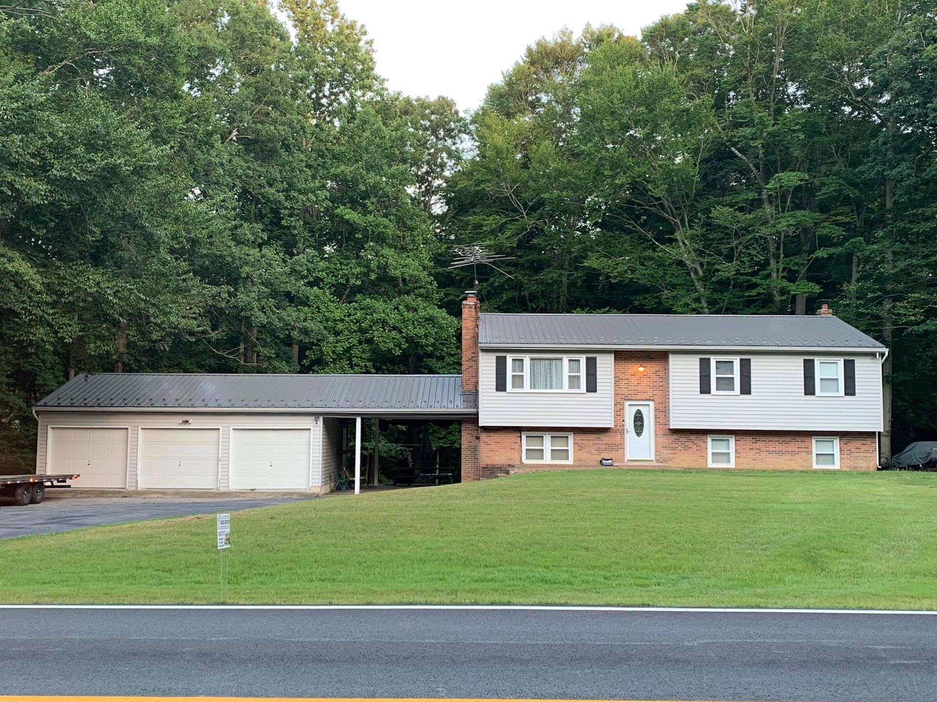 A brick house with a garage and a covered porch with metal roofing in Southern MD