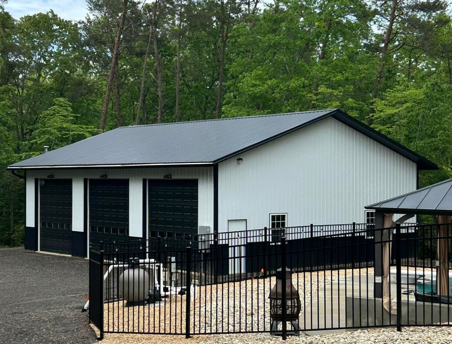 A white and black garage with a black metal roof.