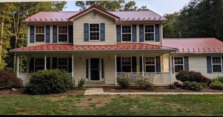 A large white house with blue shutters and a red metal roof