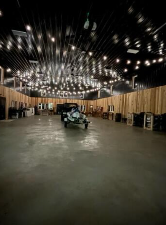 Large empty room with wood paneling, string lights, and a trailer in the center.
